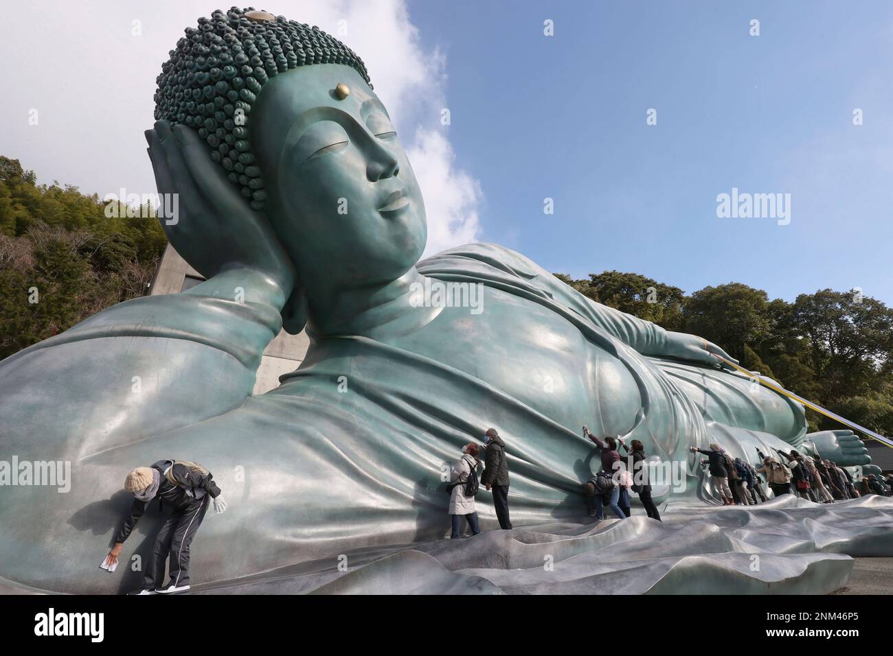 Approximately 200 Buddhist priests and believers clean a reclining