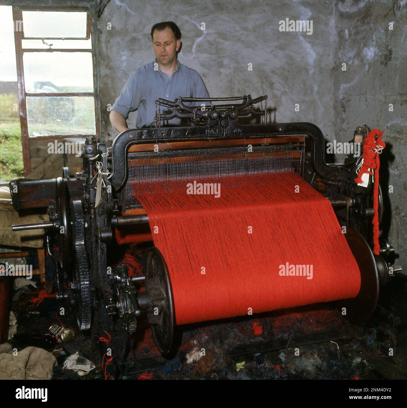 1960s, historical, inside a small crofters dwelling at Breasclete on the Isle of Lewis, in the Outer Hebrides, Scotland, UK, a man weaving Harris Tweed, the only fabric in the world to have it's own Act of Parliament. This states that all Harris Tweed is made from pure new British wool, hand woven by crofters on their crofts (small holdings) and only made on the Scottish islands of the Outer Hebrides. Stock Photo