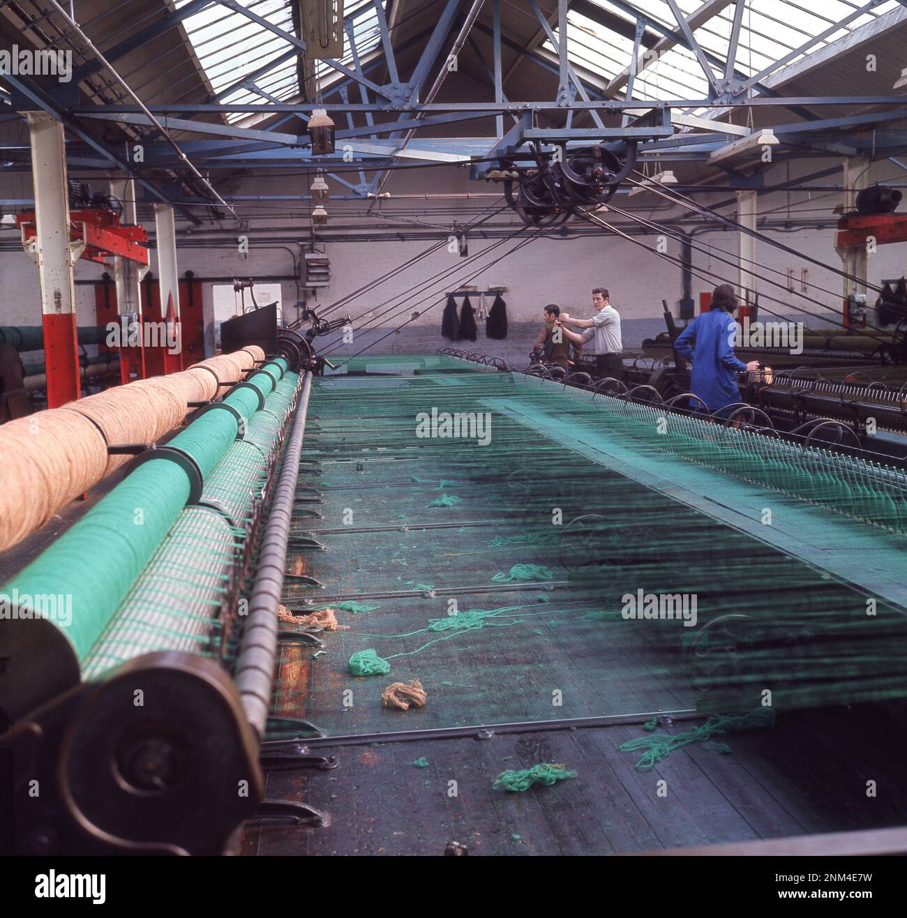 1960s, historical, inside an industrial unit, male operators using spinning machines or looms to produce the famous Harris Tweed, Stornoway, Isle of Lewis, Outer Hebrides, Scotland, UK. Stock Photo