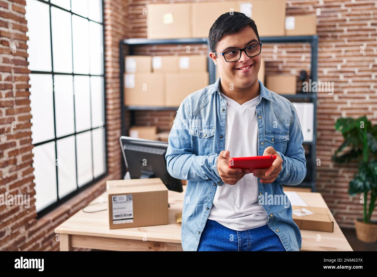 Down syndrome man ecommerce business worker using touchpad at office Stock Photo
