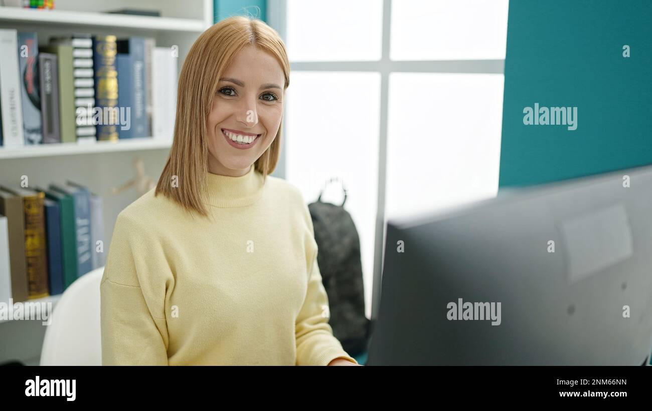 Young blonde woman student using computer studying at university ...