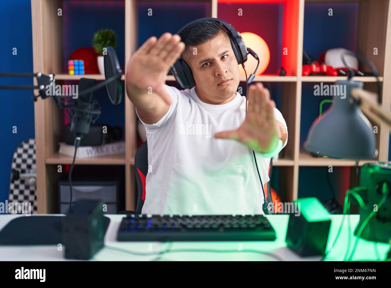 Young hispanic man playing video games doing frame using hands palms ...