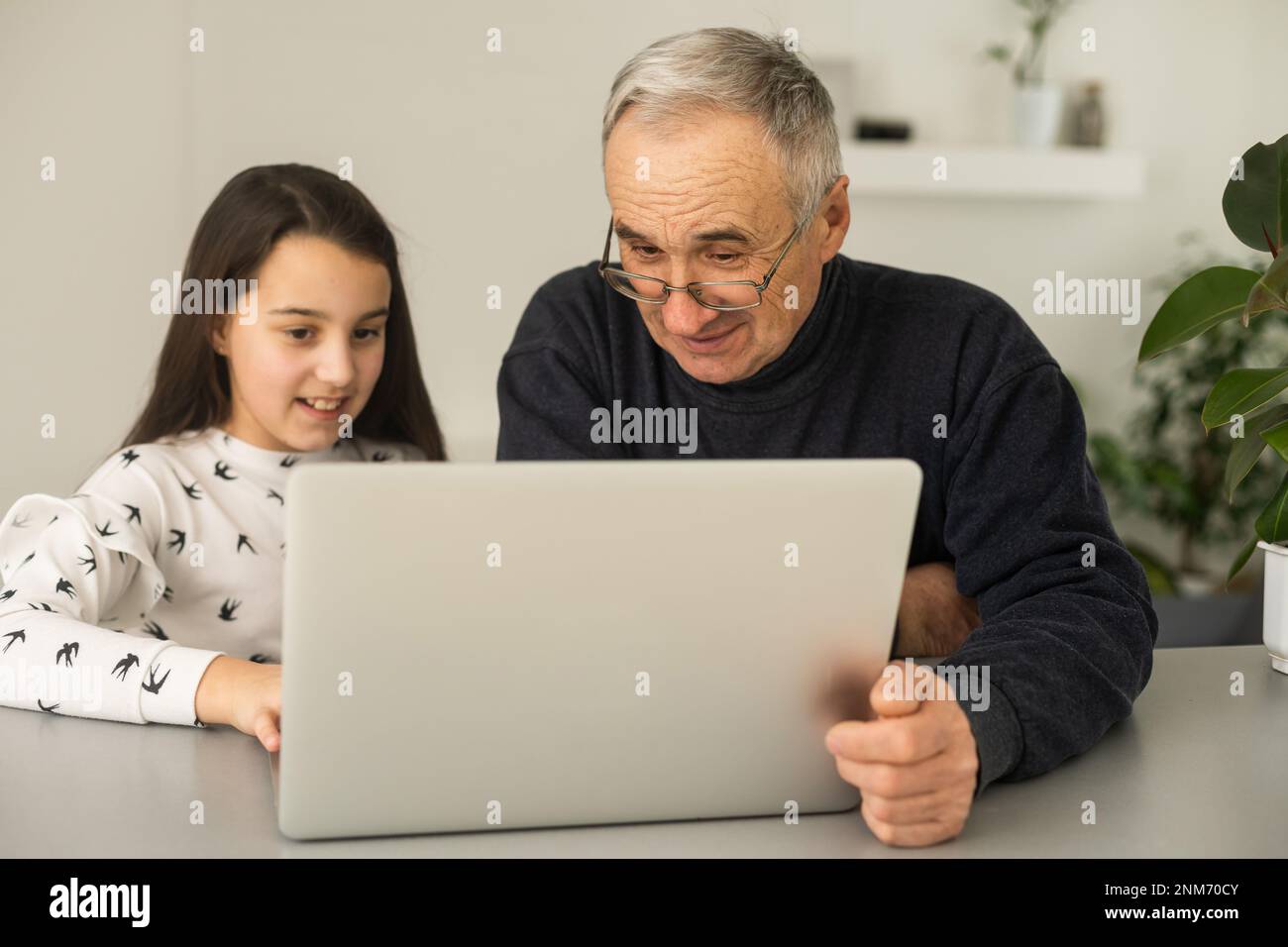 Grandfather and granddaughter spend time together use laptop, browse