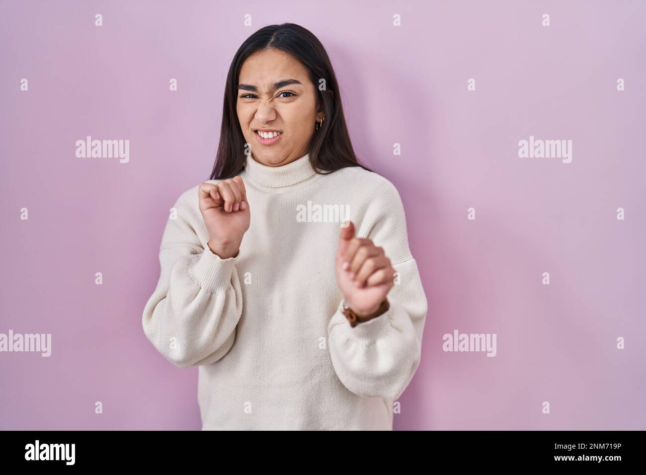 Young south asian woman standing over pink background disgusted ...