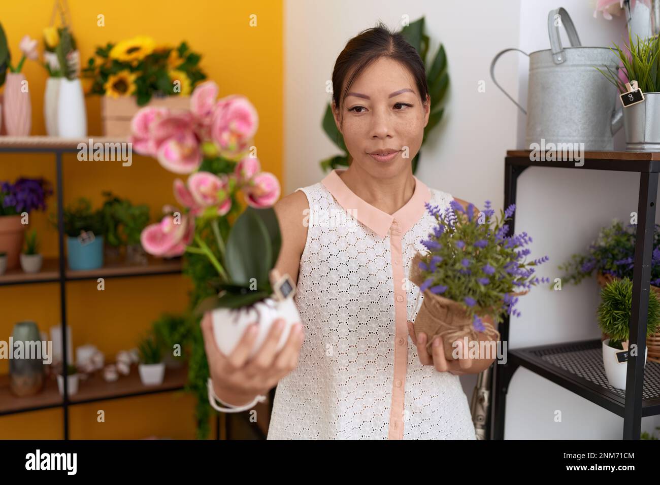 Young asian woman florist holding plants at flower shop Stock Photo - Alamy