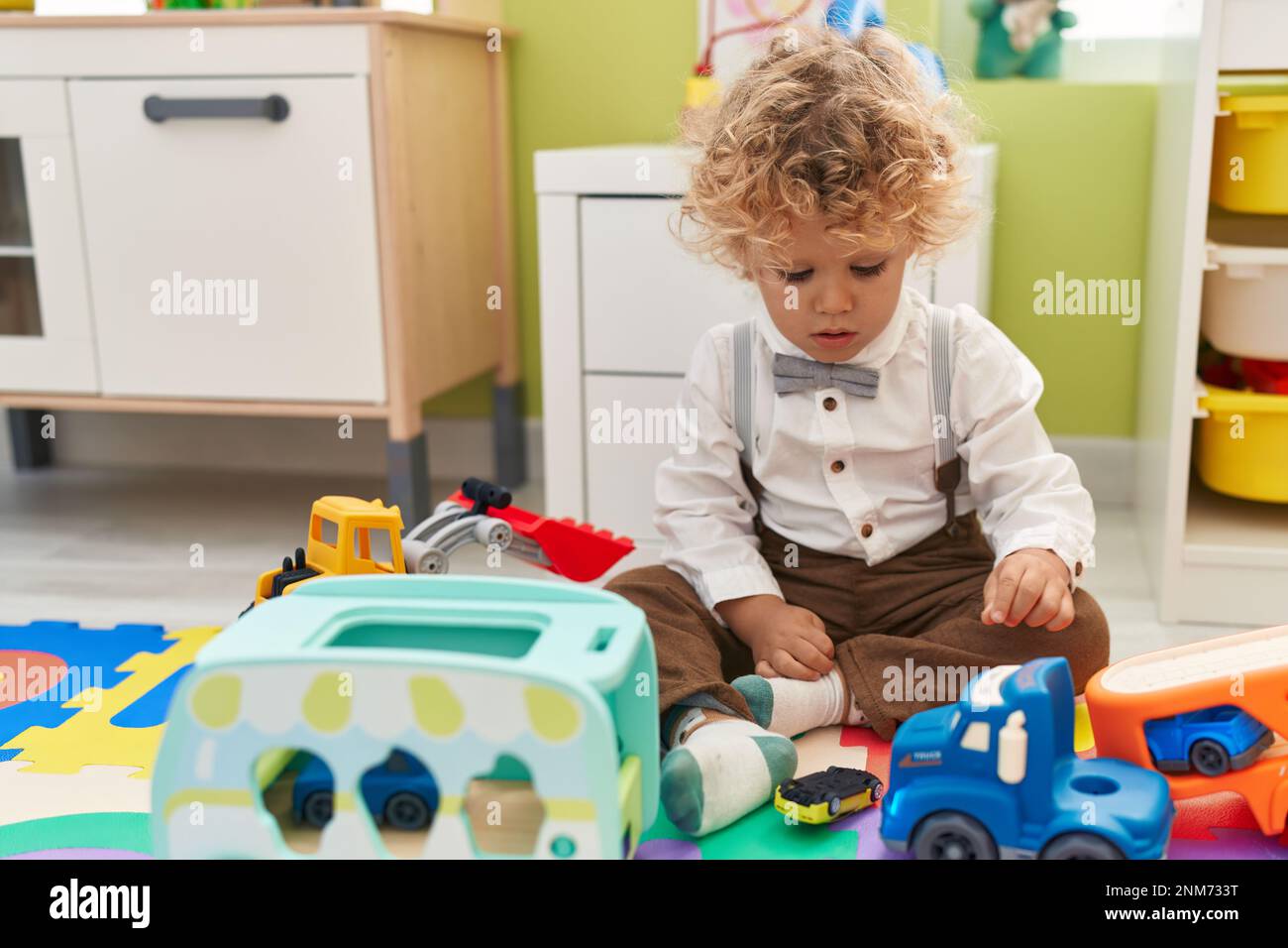 Adorable blond toddler playing with cars toy sitting on floor at ...