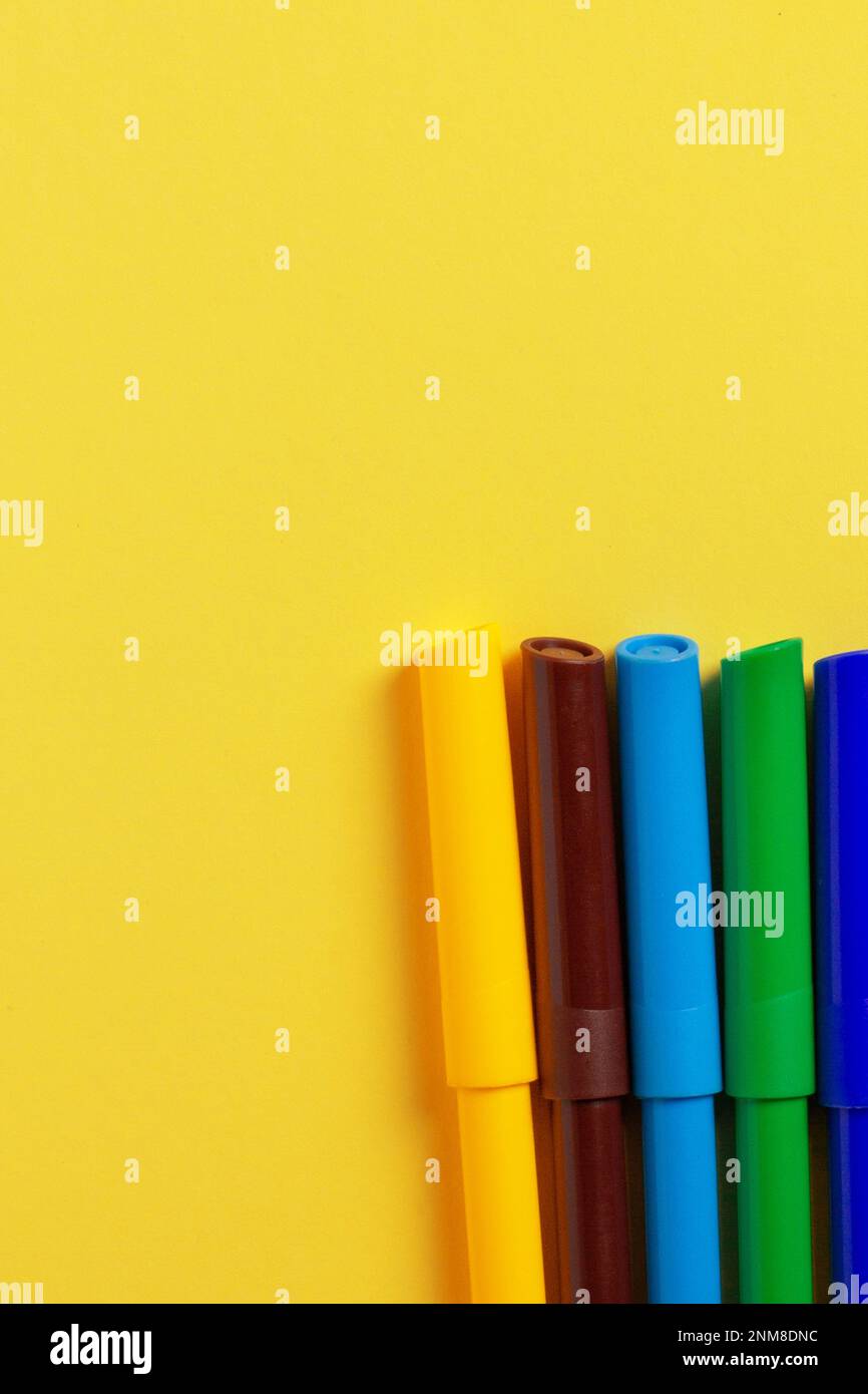 Markers of different colors on a yellow background. Stock Photo