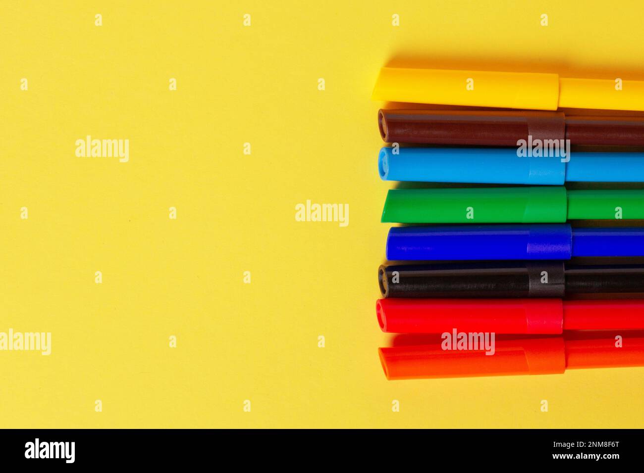 Markers of different colors on a yellow background. Stock Photo