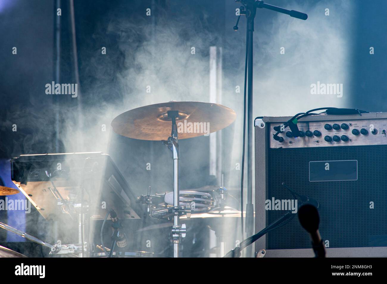 Sound reinforcement equipment, drum equipment, and microphone stands on a stage in stage smoke Stock Photo