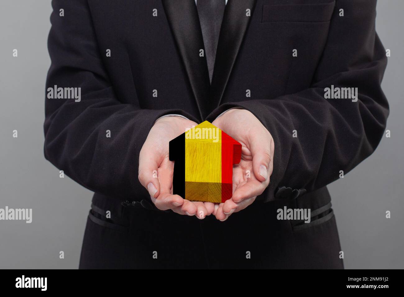 Belgian person holding wooden house with flag of Belgium Finance, investment, mortgage, loan and credit concept Stock Photo