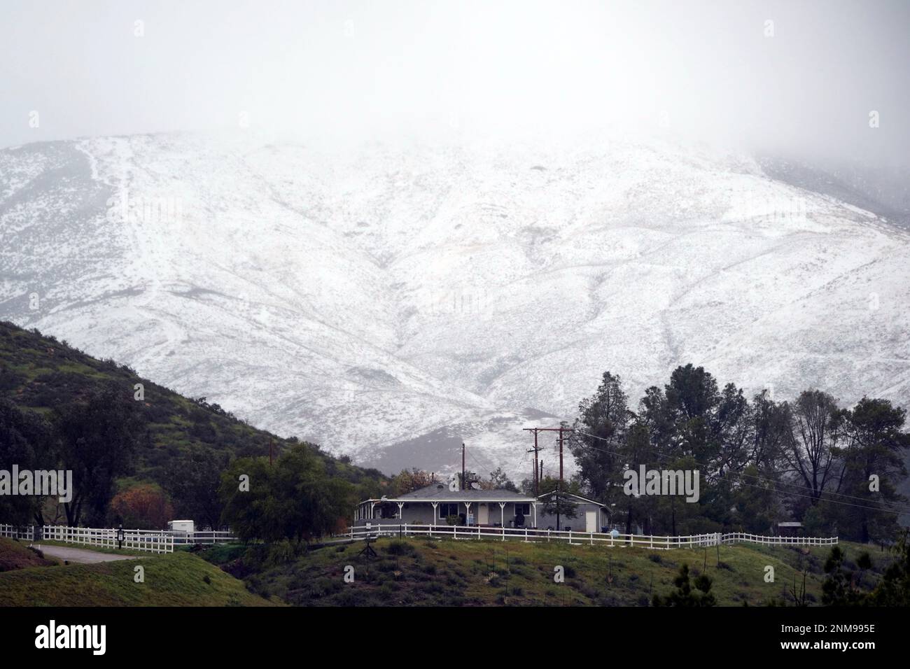 Snow accumulates on a hillside over a property Friday, Feb. 24, 2023