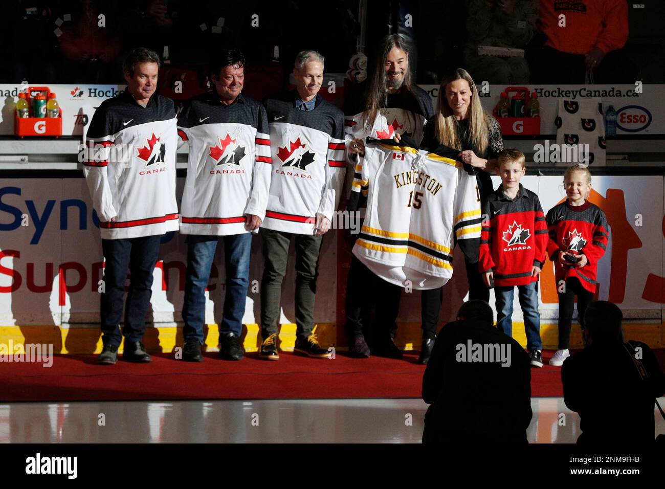 Jayna Hefford, third from right, is presented with a hockey jersey from  members of "The Tragically Hip" before her own jersey is raised to the  rafters prior to Rivalry series hockey game