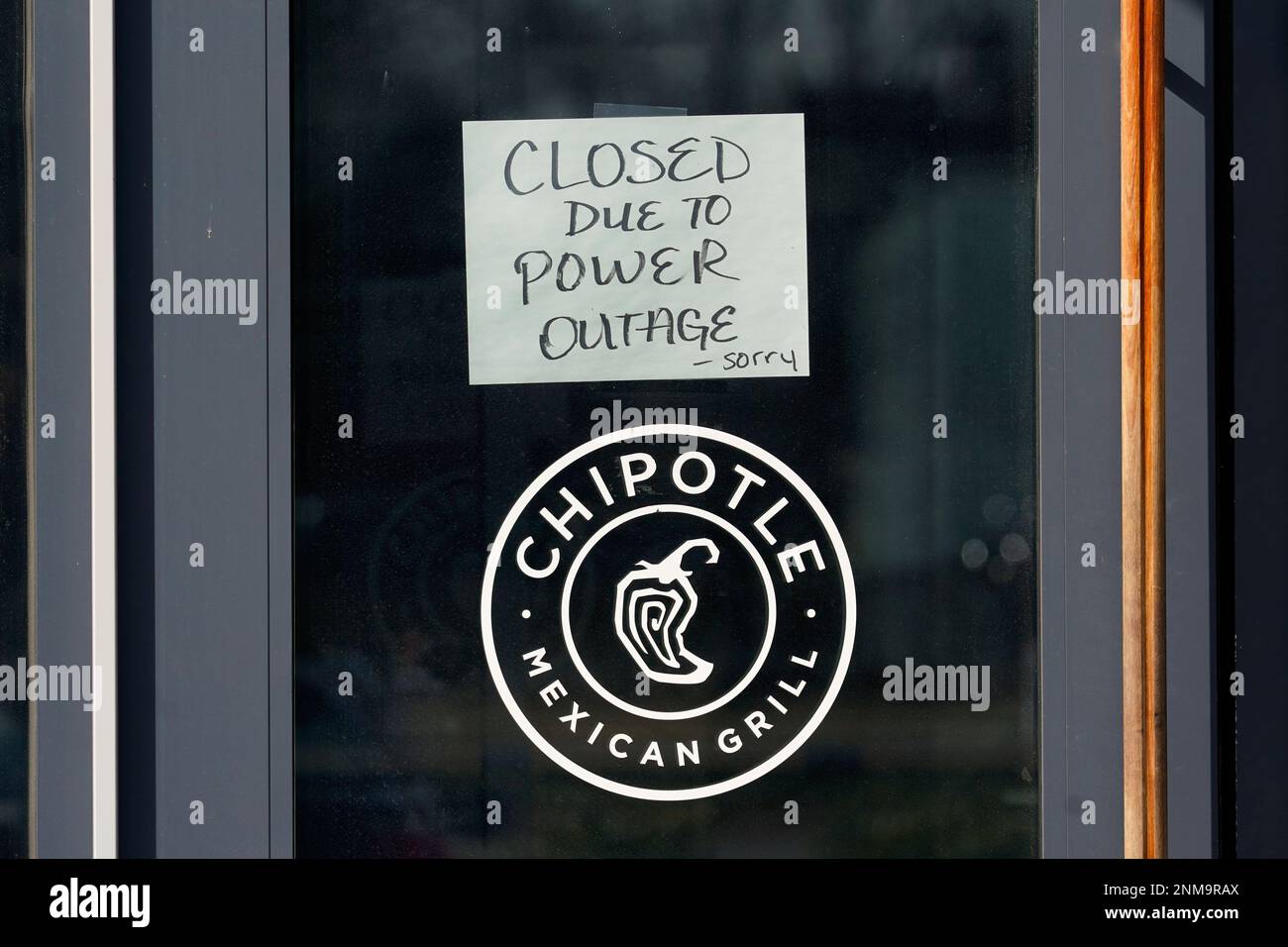 A closed due to power outage sign hangs on the door at a Chipotle