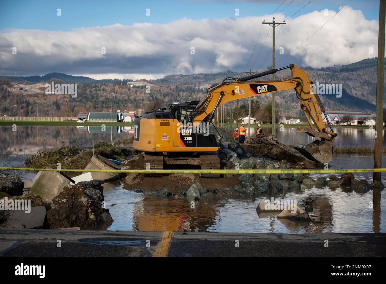 Workers use heavy equipment to move rocks where Cole Road and a dike ...
