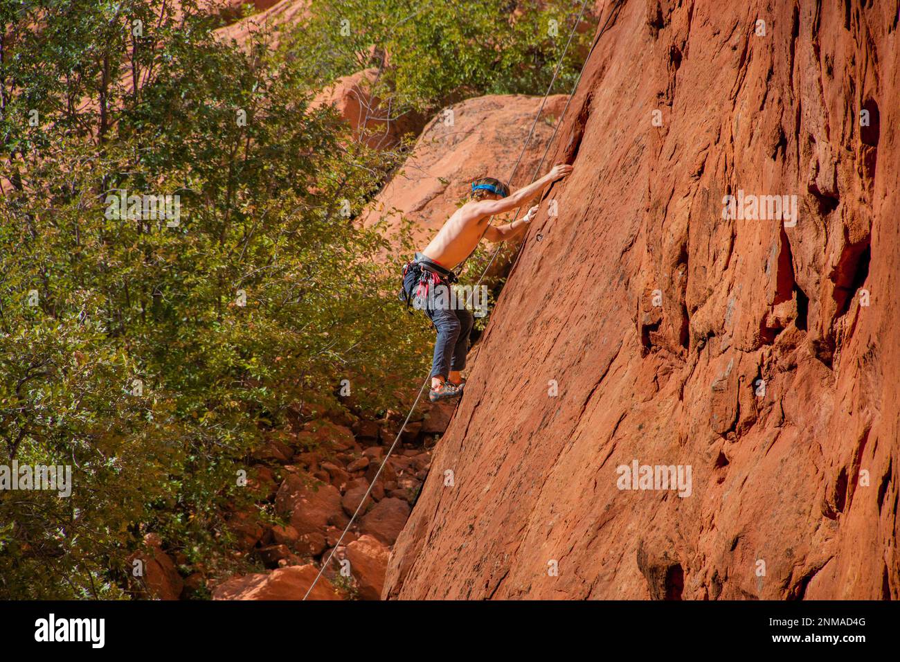 Young man climbing red eroded cliff in Garden of the Gods Colorado USA Stock Photo