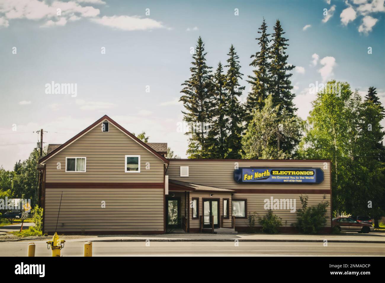 06-21-2023 Fairbanks, USA - Structure with Far North Electronics sign located in Fairbanks, Alaska - Tall evergreen trees in background Stock Photo