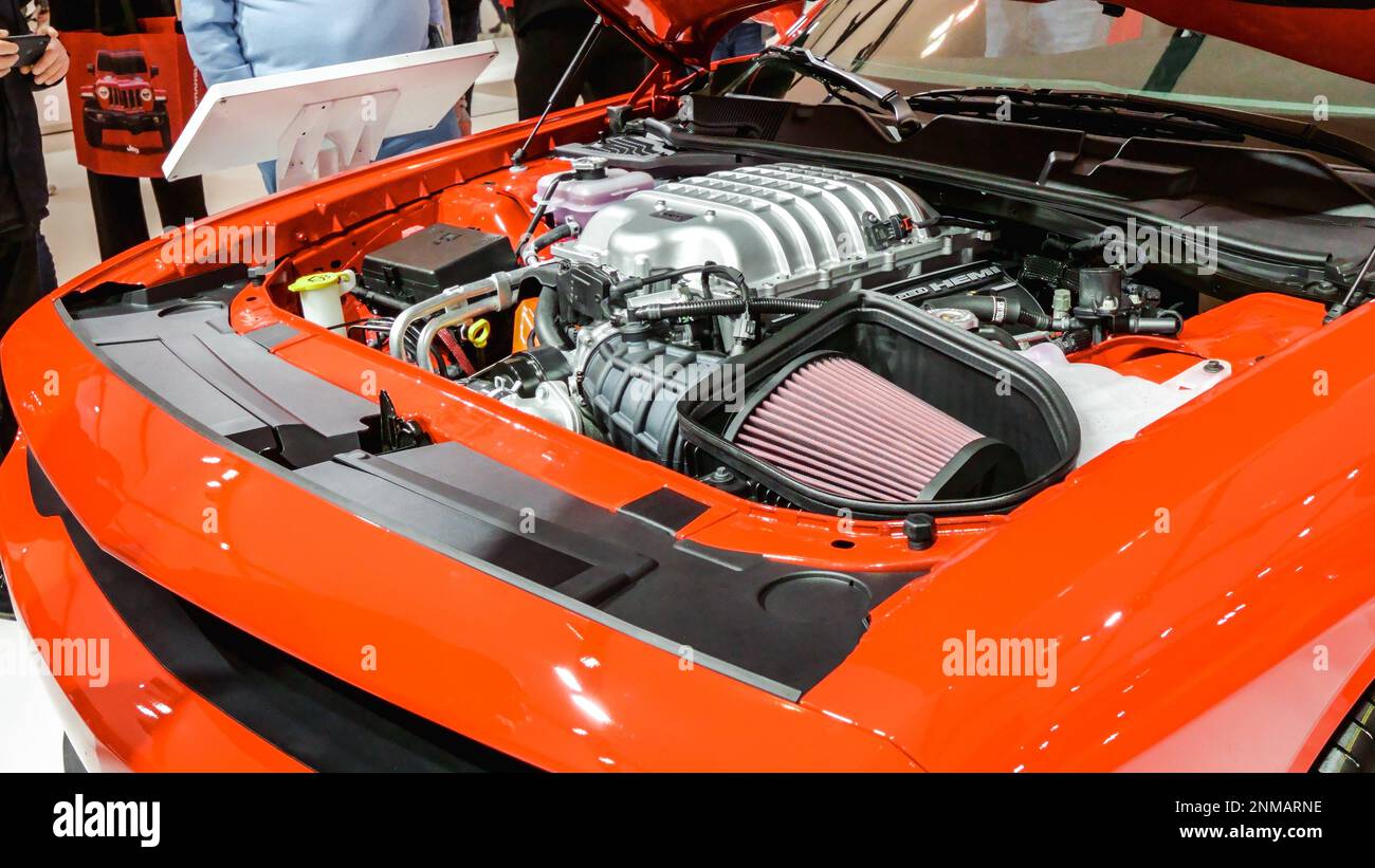 Close view of motor of red Jeep car on display. Crowds looking at new car models at Auto show