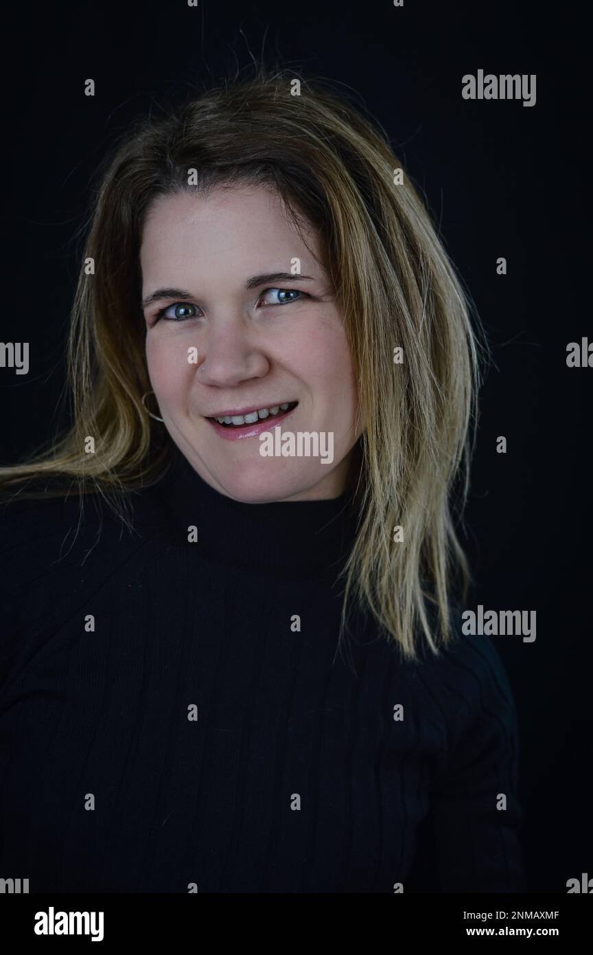 feigning a smile - portrait of a beautiful blonde woman who smiles forcedly and not spontaneously Stock Photo