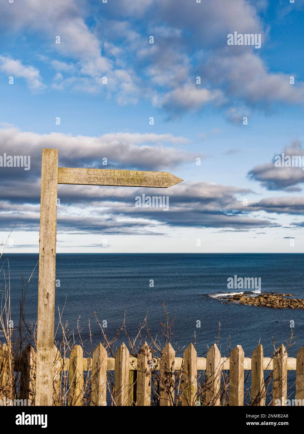 Coastline and countryside sign against a blue sky with cloud background ...