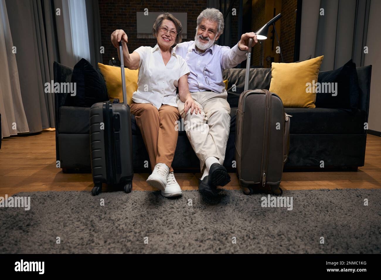 Old couple arrived at hotel, resting on couch Stock Photo