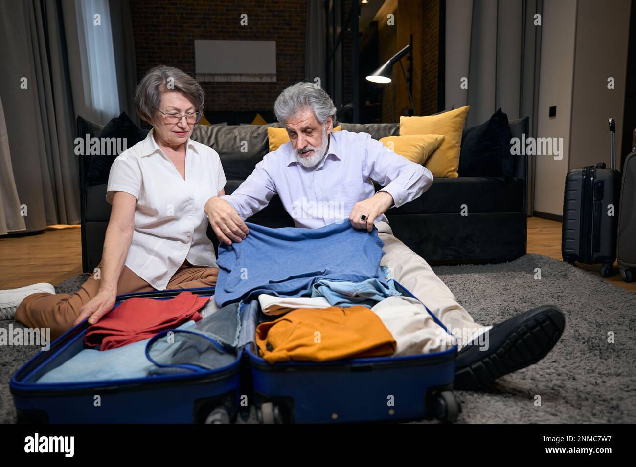 Old man folds clothes in trolley bag Stock Photo Alamy