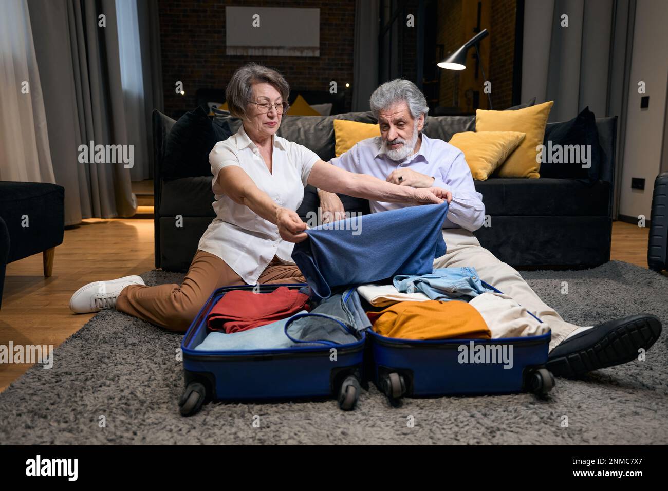 Happy couple folds clothes in trolley bag Stock Photo Alamy