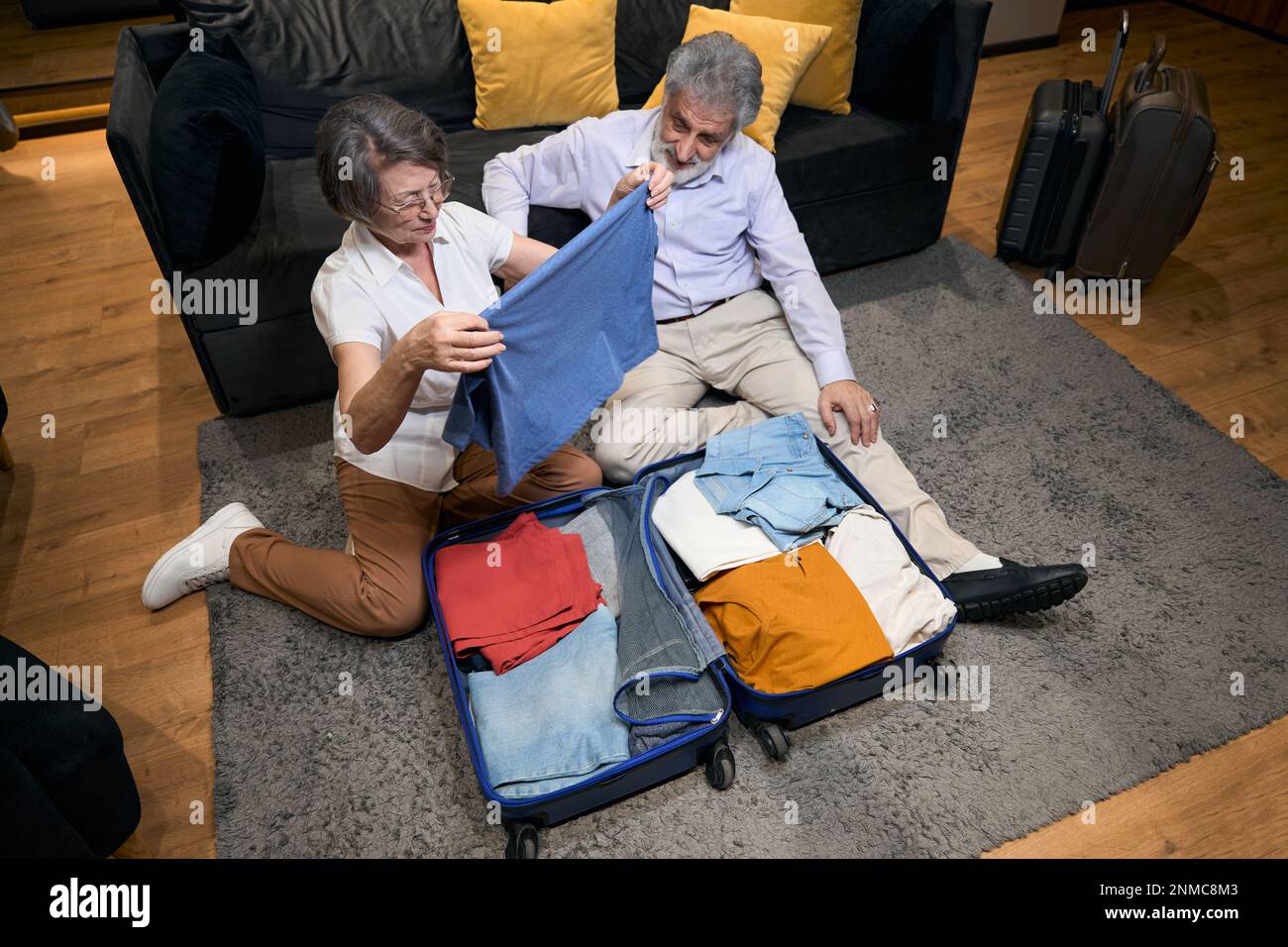 Old lady helping husband fold clothes in trolley bag Stock Photo Alamy