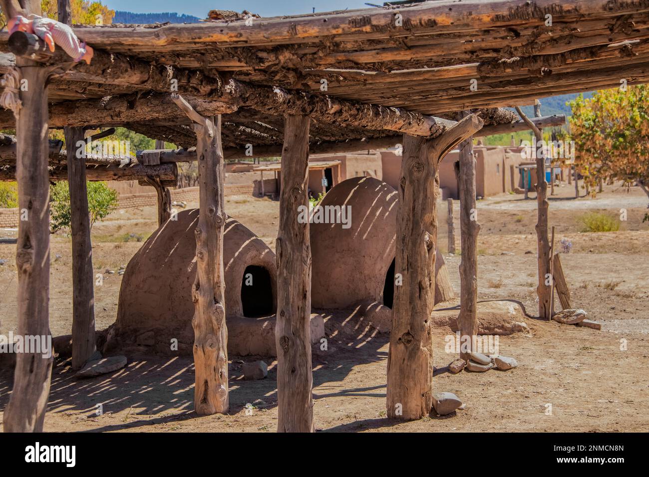Two hornos-traditional earthen ovens- underneath a drying rack with a childs doll left on the corner - Homes of the Ute Pueblo in Taos New Mexico in t Stock Photo