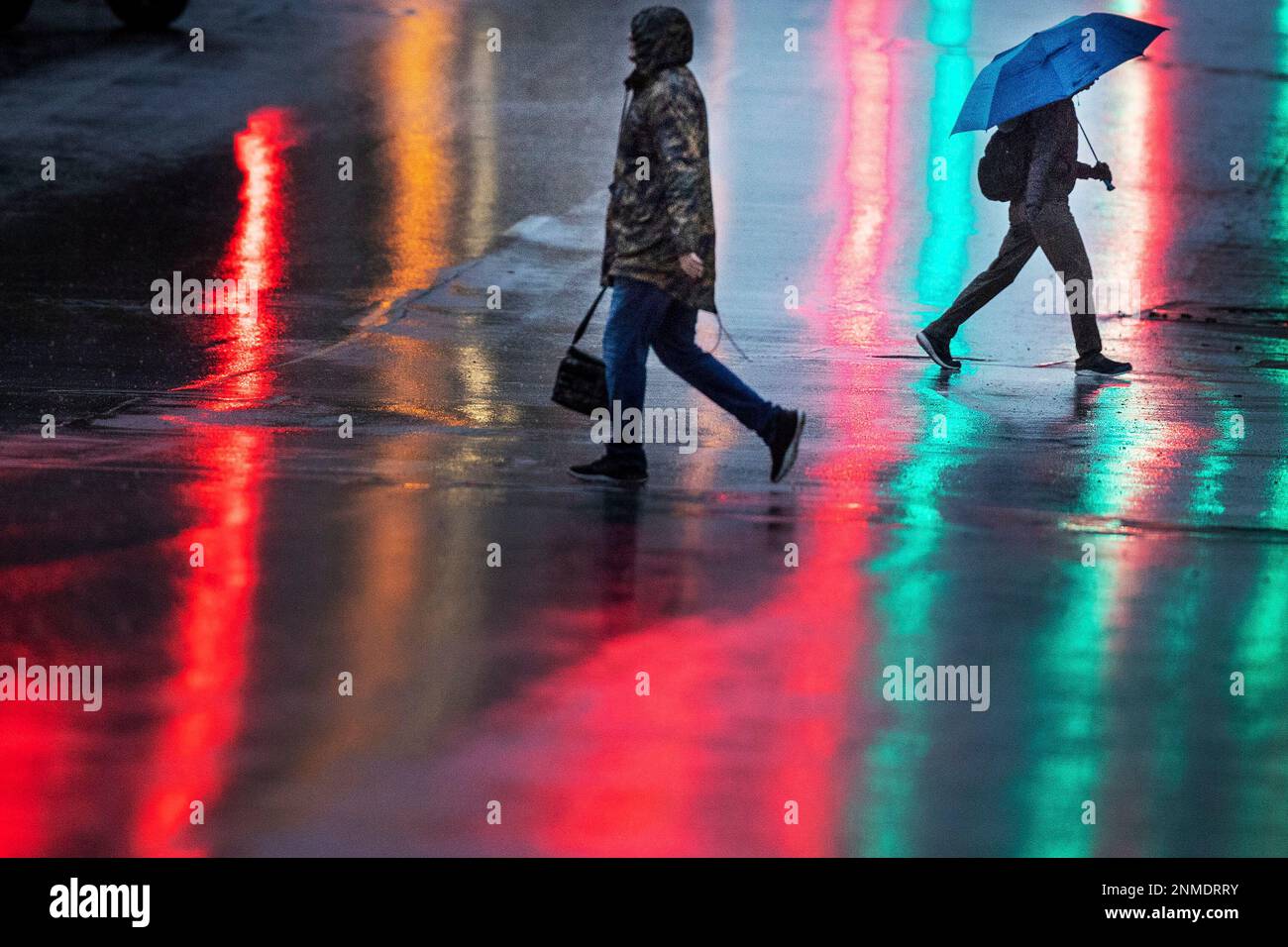Pedestrians cross Farnam Street at 15th Street in the rain in Omaha