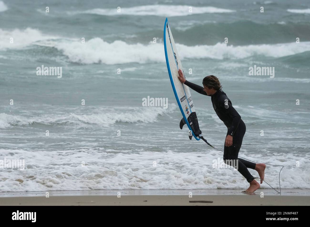 A surfer pushes his board in to the wind on Friday, Feb. 24, 2023, in