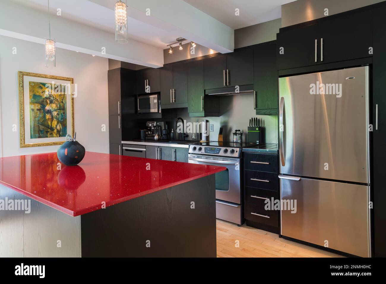 Black melamine cabinets and island with red quartz countertop in kitchen inside modern home Stock Photo