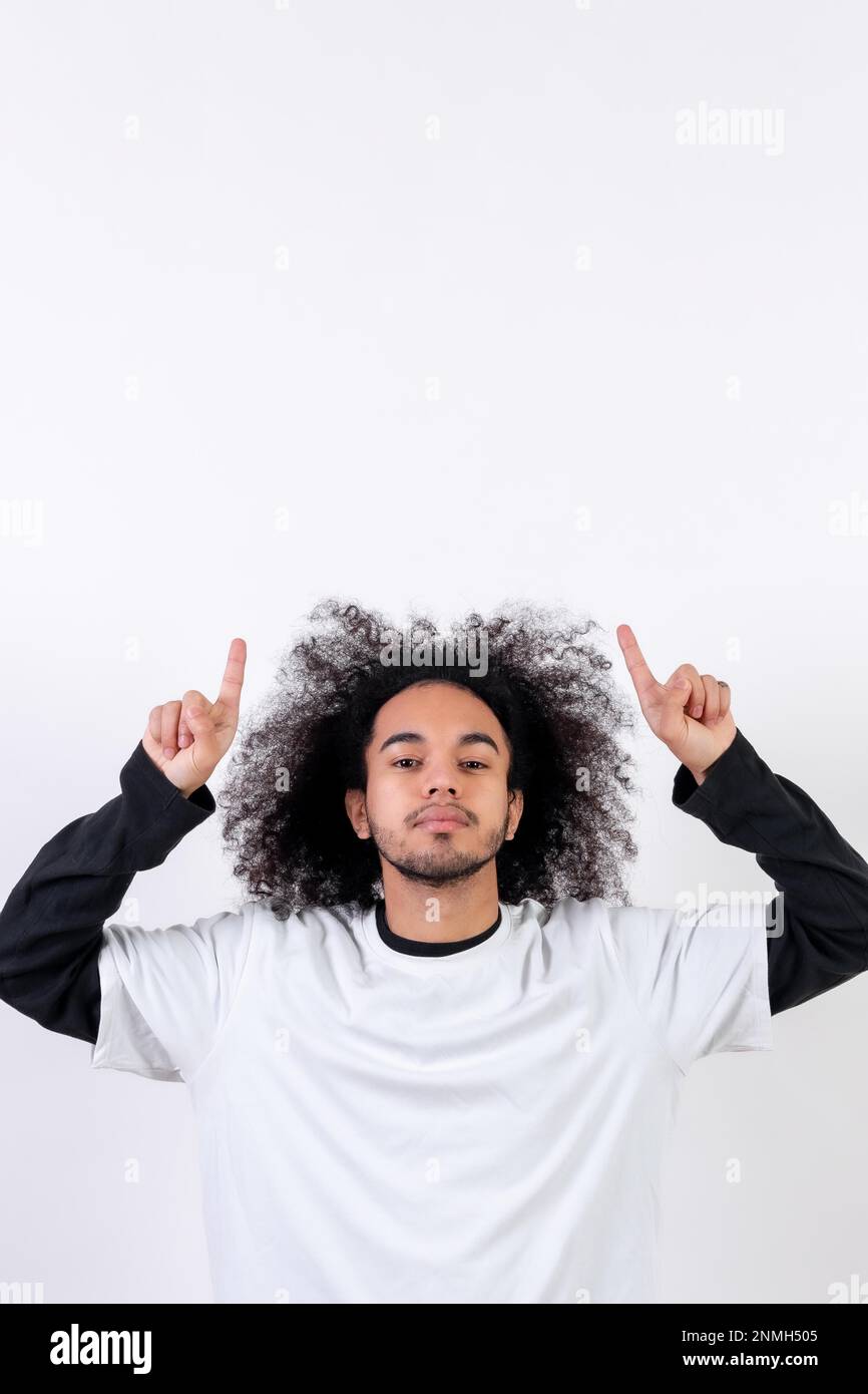 Pointing above a copy paste space. Young man with afro hair on white background Stock Photo