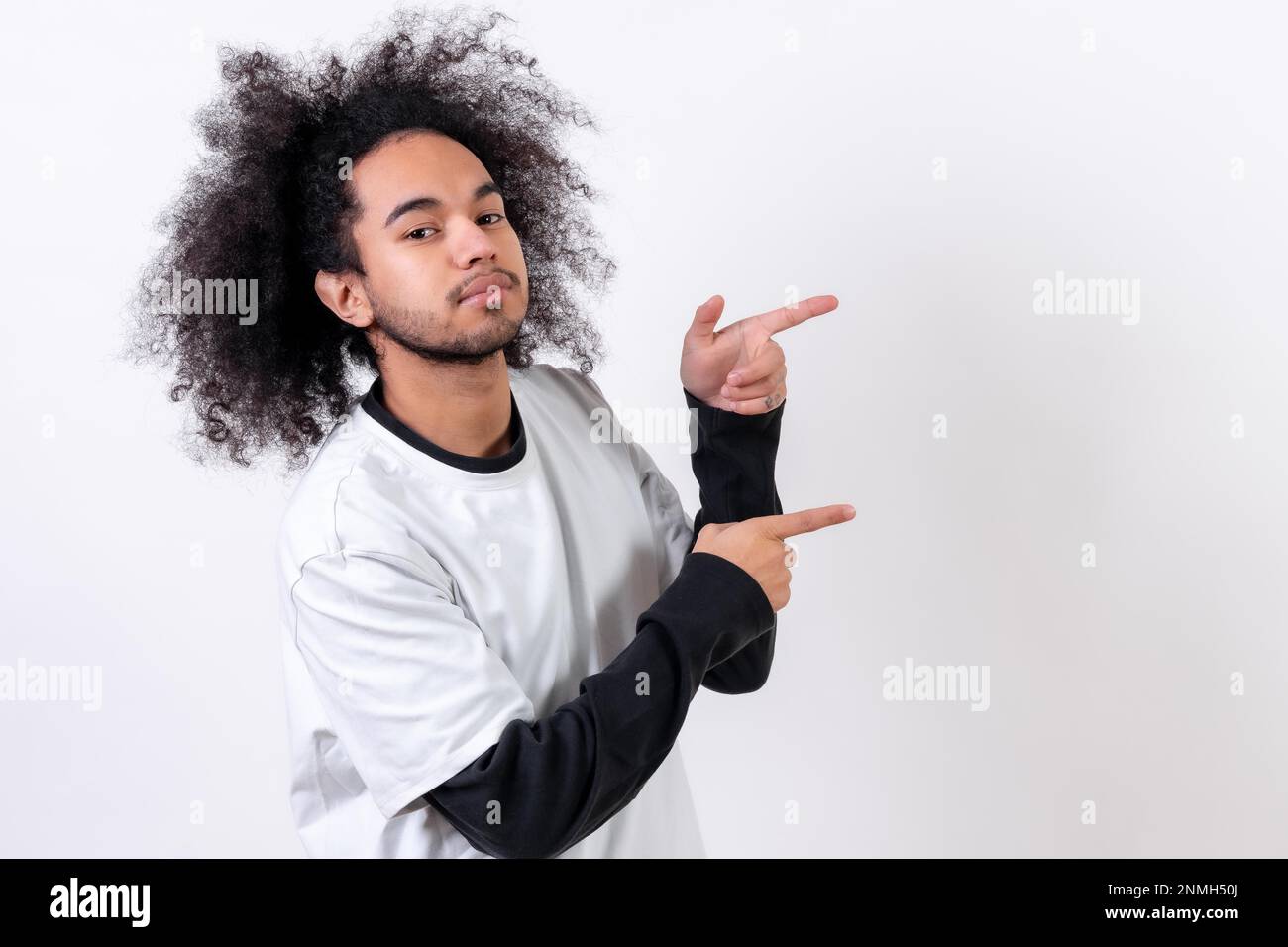 Pointing to the right at a copy paste space. Young man with afro hair on white background Stock Photo