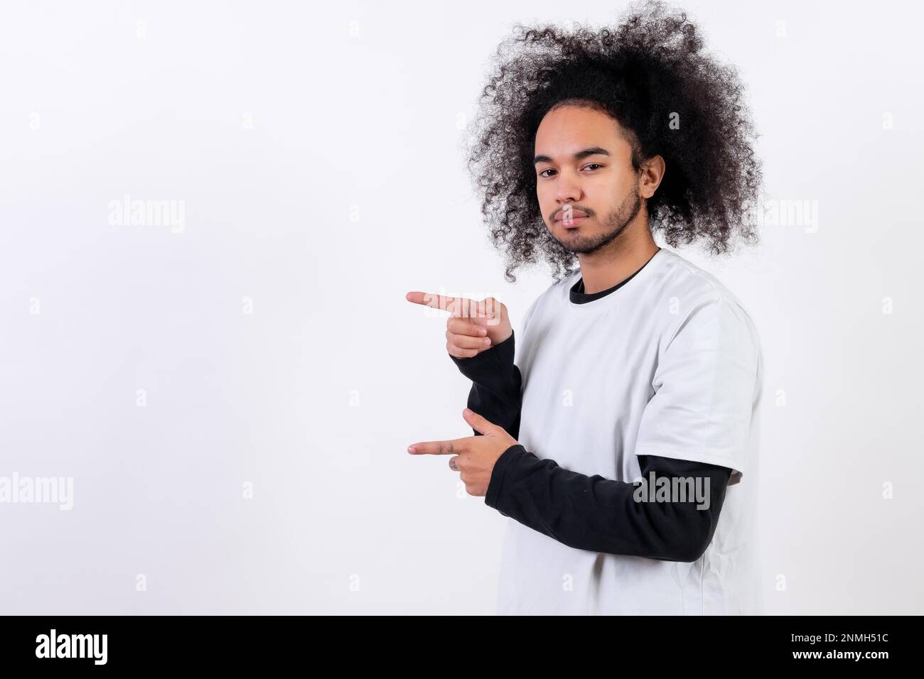 Pointing to the left at a copy paste space. Young man with afro hair on white background Stock Photo