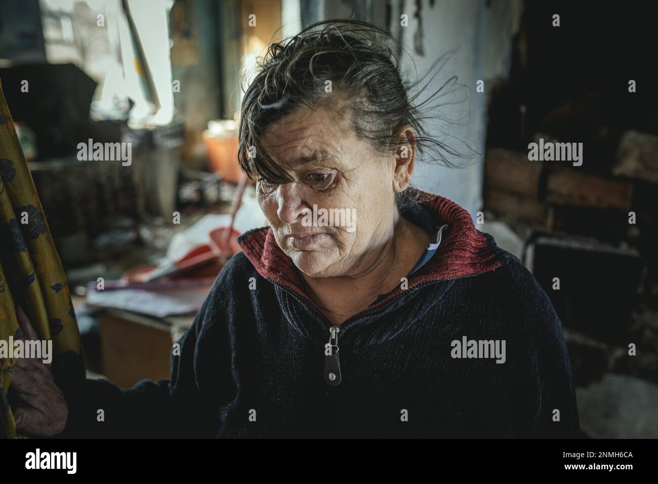 Tatjana, 60, in the ruins of the house she had lived in with her family in front of it was destroyed in a Russian missile attack, her man Viktor and Stock Photo