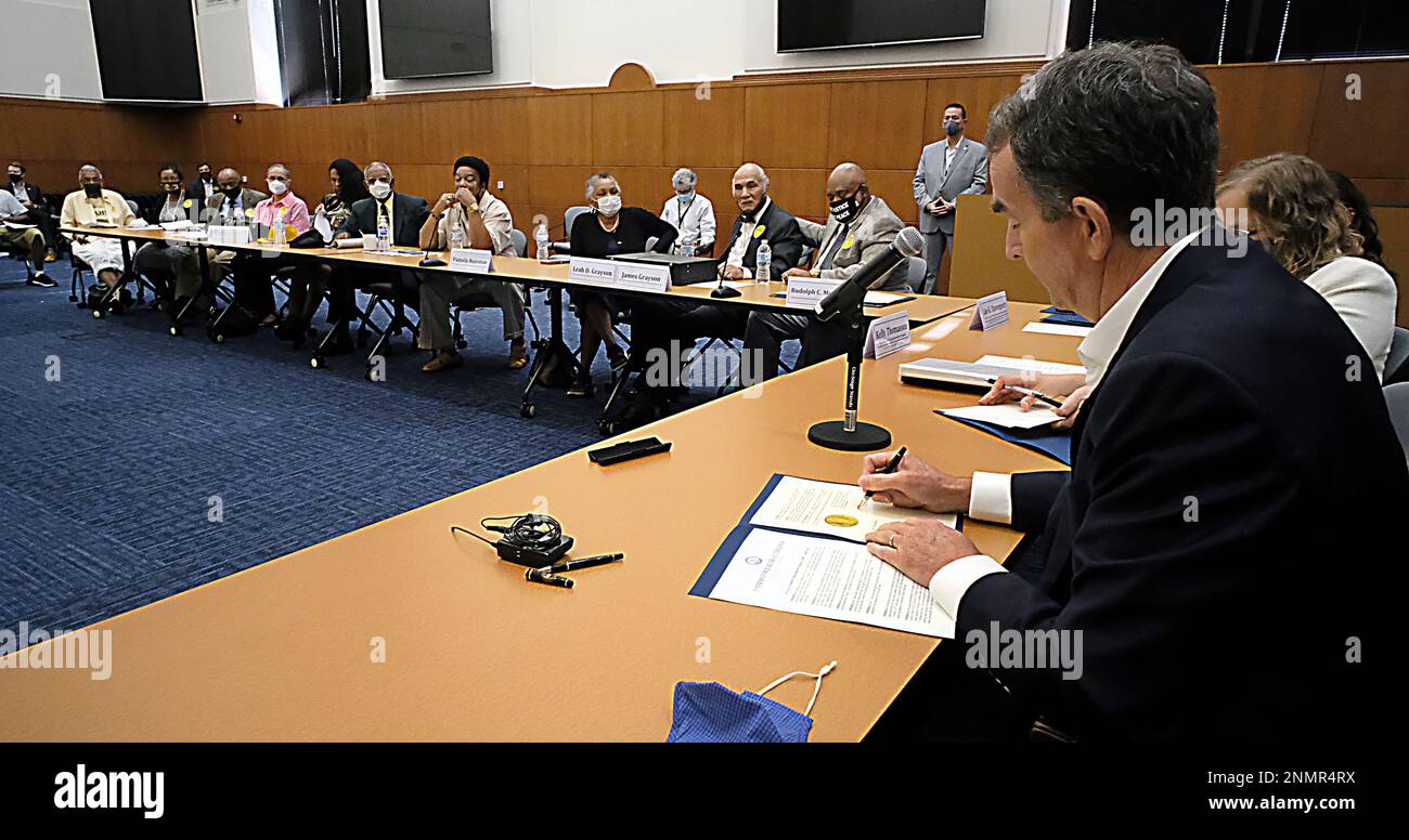 Virginia Gov. Ralph Northam, right, signs posthumous pardons for the