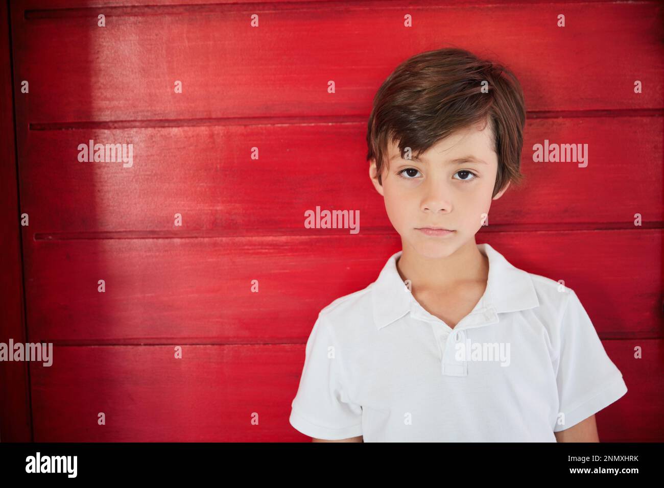 Feeling blue today. Portrait of a sad little boy standing against a red ...