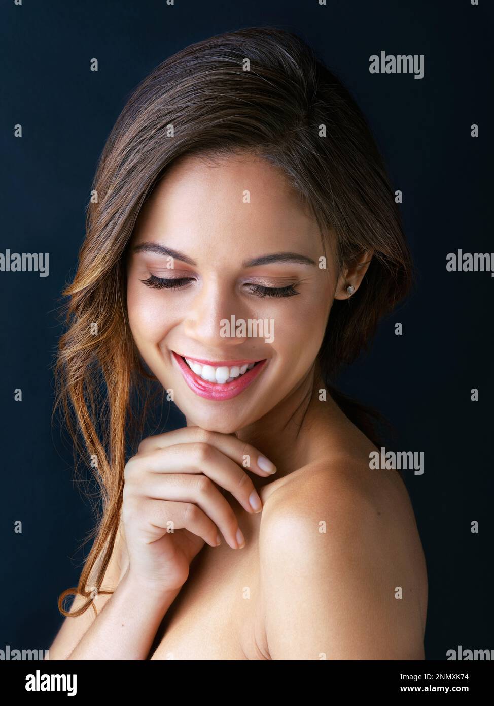 My skincare regimen works wonders. a beautiful young woman posing against a dark background. Stock Photo