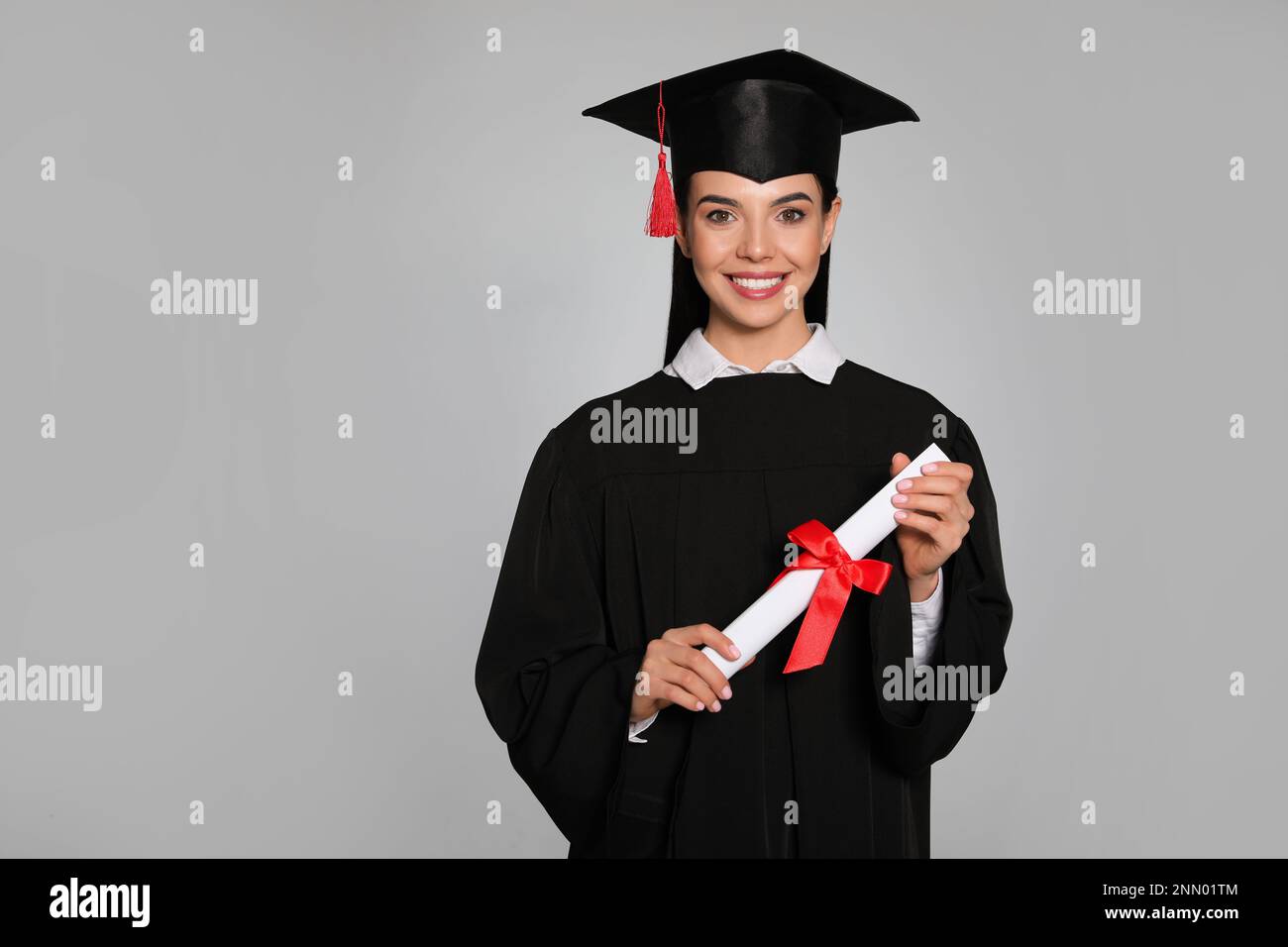 Happy student with graduation hat and diploma on grey background. Space ...