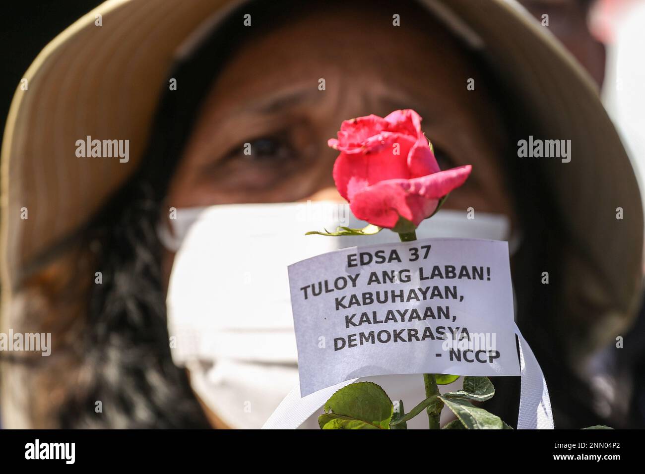 Quezon, Philippines. 25th Feb, 2023. A protester holds a rose with a protest message during a demonstration. Demonstrators hold a protest in the EDSA People Power monument in celebration of the 37th anniversary of the People Power Revolution. It is also the first People Power Anniversary under Marcos Jr.'s administration. Credit: SOPA Images Limited/Alamy Live News Stock Photo