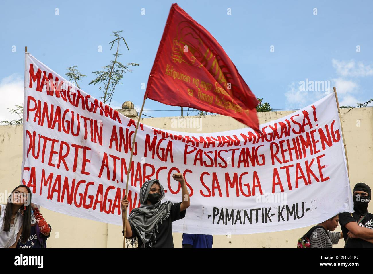 Quezon, Philippines. 25th Feb, 2023. Protesters hold a flag and a banner expressing their opinion during a demonstration. Demonstrators hold a protest in the EDSA People Power monument in celebration of the 37th anniversary of the People Power Revolution. It is also the first People Power Anniversary under Marcos Jr.'s administration. Credit: SOPA Images Limited/Alamy Live News Stock Photo