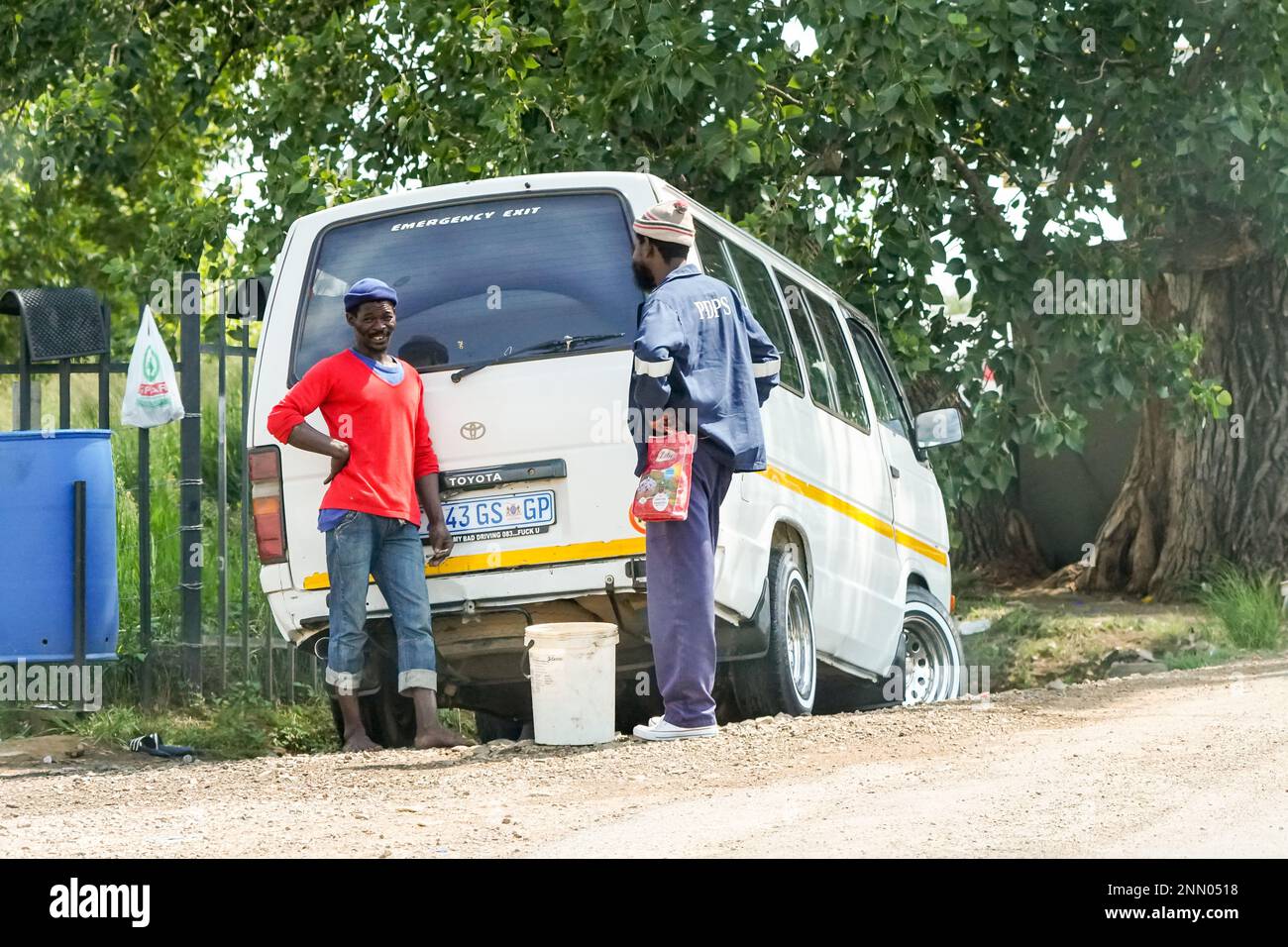 daily life in Africa, two African men friends having a chat against a taxi on the side of the road in South Africa, authentic lifestyle street photo Stock Photo