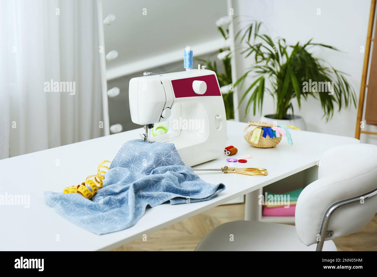 Modern sewing machine, fabric and accessories on table indoors Stock
