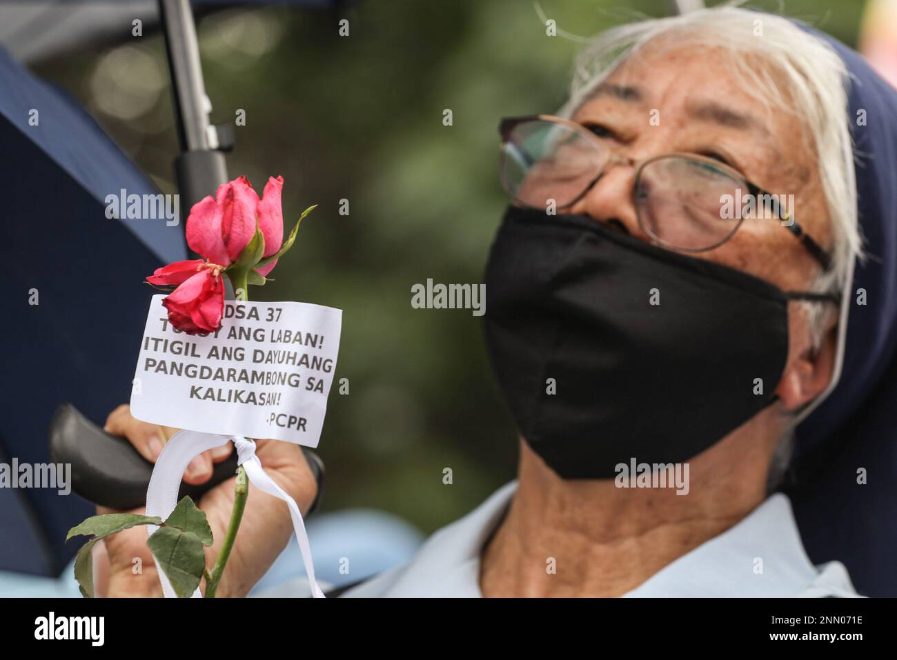 Quezon, Philippines. 25th Feb, 2023. A nun holds a rose during a demonstration. Demonstrators hold a protest in the EDSA People Power monument in celebration of the 37th anniversary of the People Power Revolution. It is also the first People Power Anniversary under Marcos Jr.'s administration. (Photo by Earvin Perias/SOPA Images/Sipa USA) Credit: Sipa USA/Alamy Live News Stock Photo