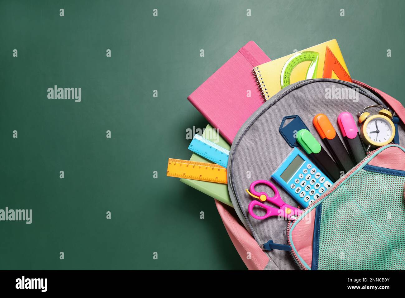 Backpack with different stationery on chalkboard background, top view. Space for text Stock Photo