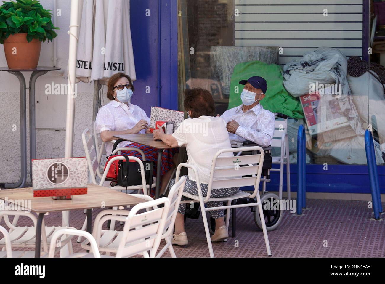 Elderly people with masks converse sitting on the terrace of a bar