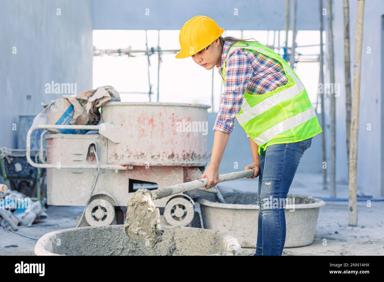 asian woman worker hardworking as a labor staff in construction site work mix concrete cement by hand Stock Photo