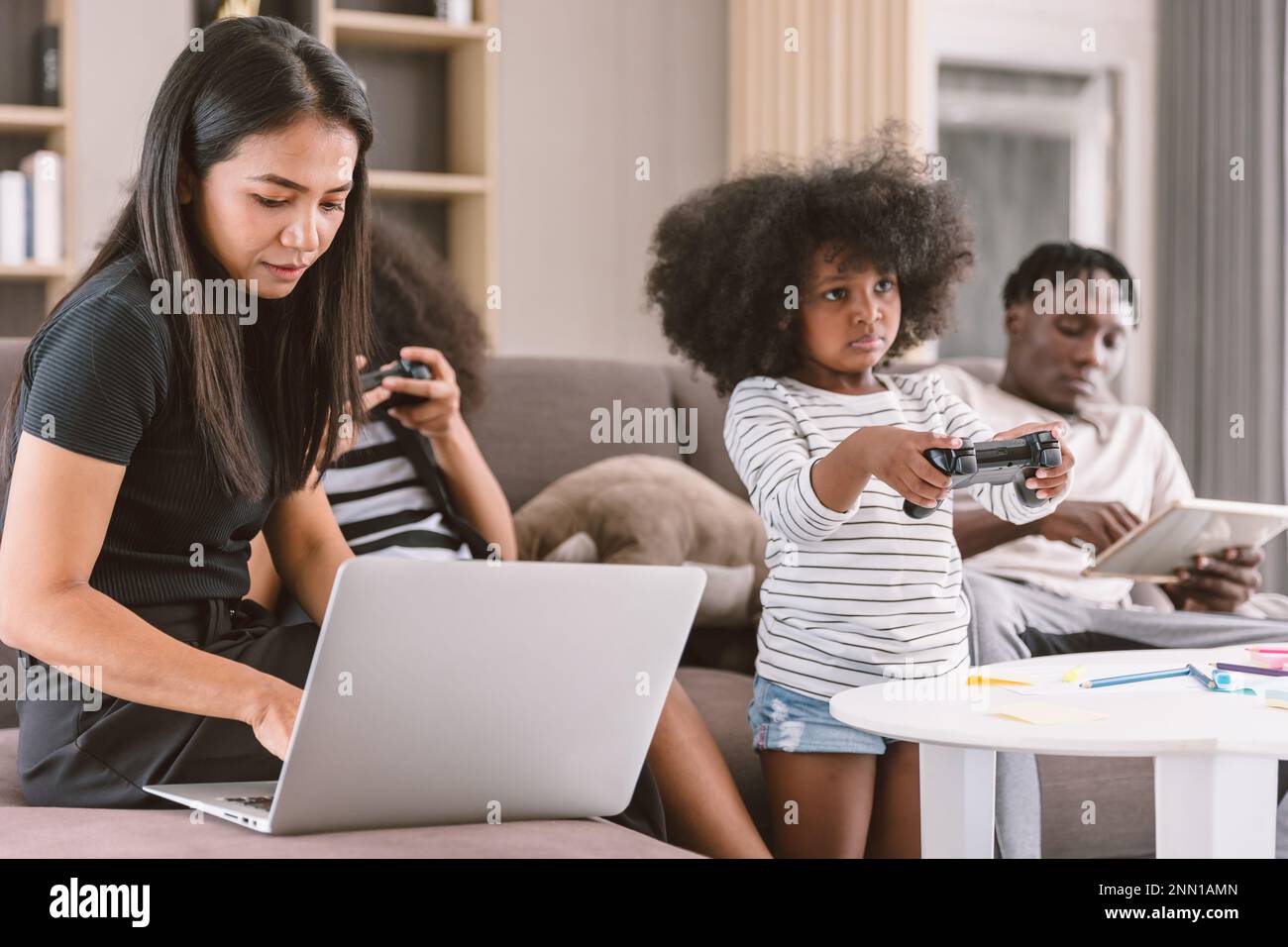 Business mom working woman busy mother holiday wireless work on laptop computer at home with daughter and family Stock Photo