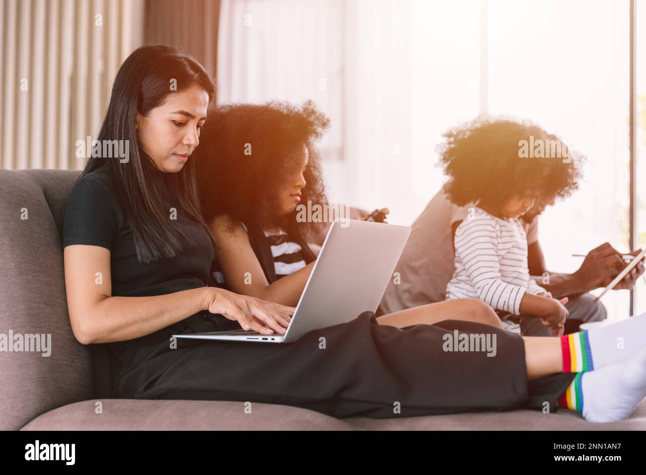 Business mom working woman busy mother holiday wireless work on laptop computer at home with daughter and family Stock Photo