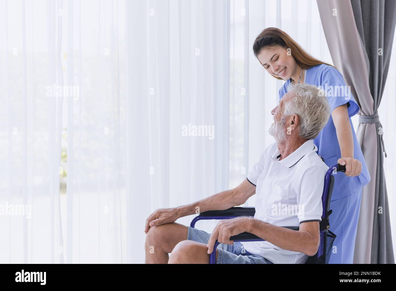 Nurse care elderly senior old man at home retirement people recovery on wheelchair. Stock Photo